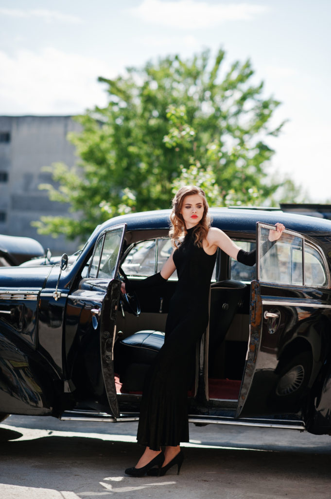 Portrait of beautiful sexy fashion girl model with bright makeup in retro style near vintage car